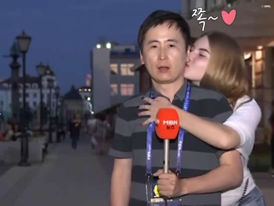 South Korean reporter Kwon Qwal Yel is kissed by two female fans during World Cup coverage